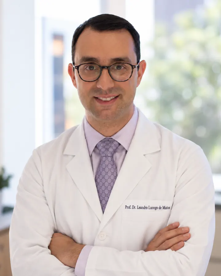 Prof. Dr. Leandro Luongo de Matos, cirurgião de cabeça e pescoço em São Paulo, de jaleco branco e braços cruzados